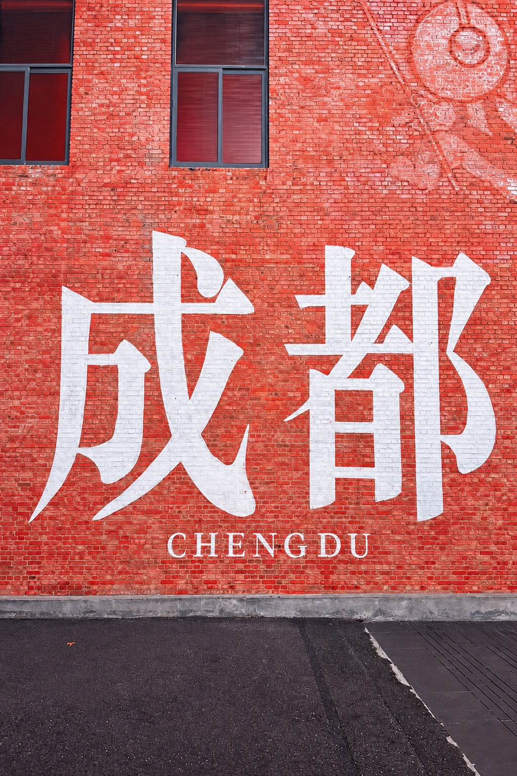 Chengdu-Motiv mit den weißen Schriftzeichen 成都 und dem Schriftzug CHENGDU auf einer roten Backsteinfassade
